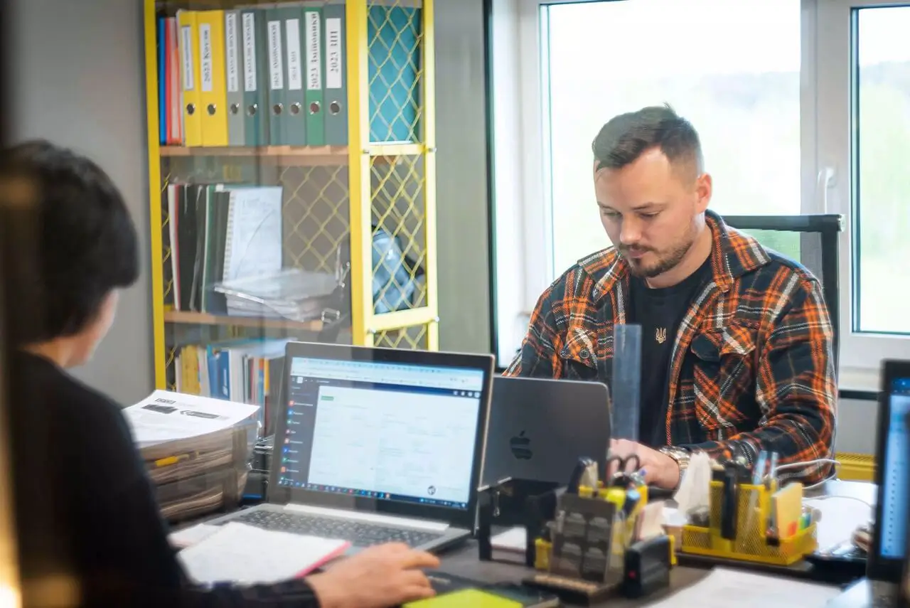 Inżynier wsparcia technicznego analizujący dokumentację projektową na stanowisku obsługi klienta